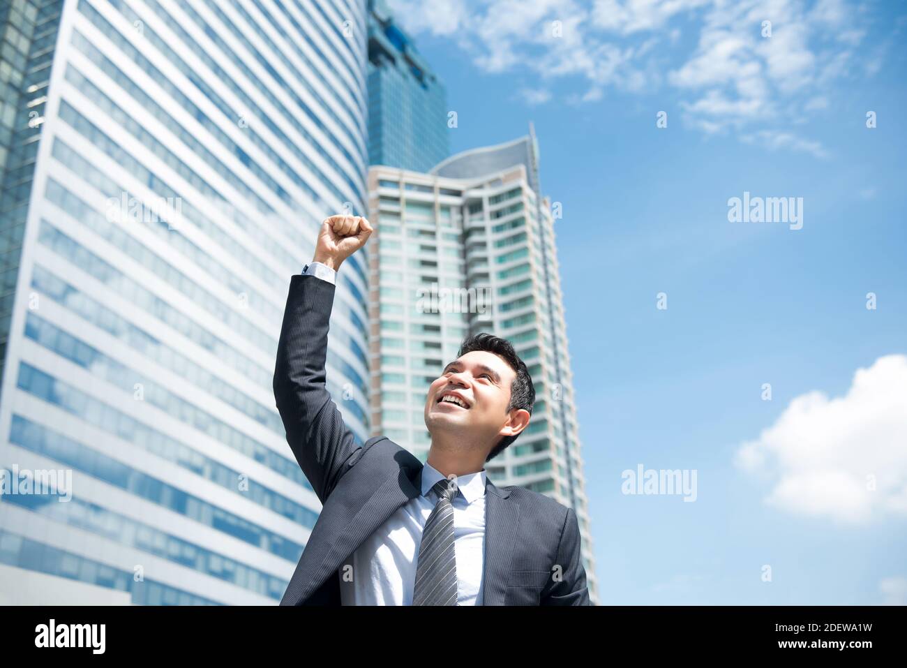 Happy delighted powerful Asian businessman raising his fist in the air ...