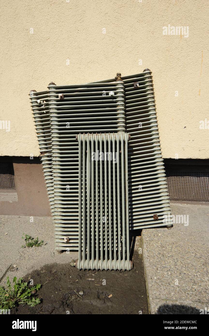 old radiators leaning against the wall of a house, convector heating