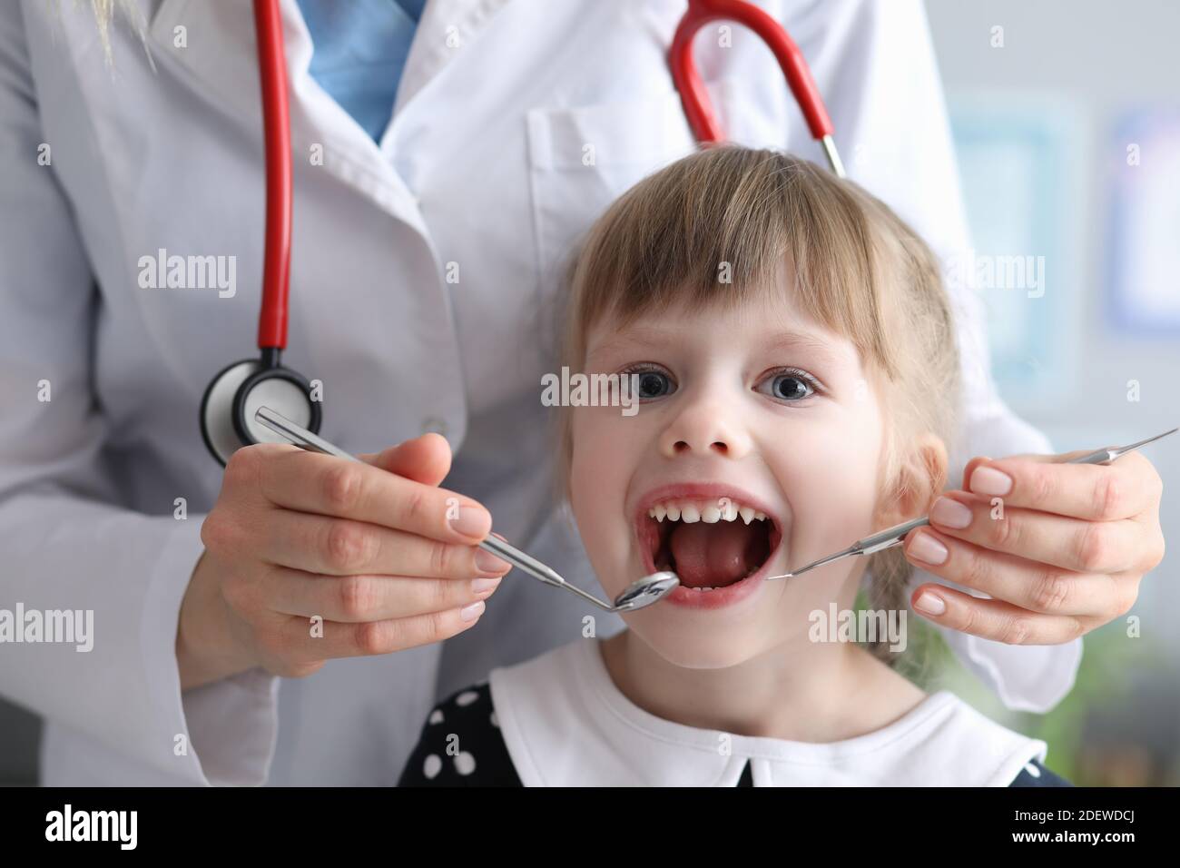 Dentist doctor with stethoscope examines teeth of little girl in clinic  Stock Photo - Alamy