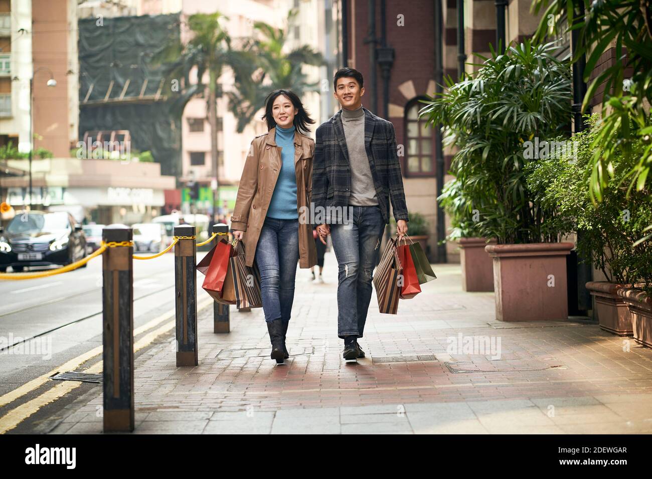 happy and loving young asian couple walking on street with shopping ...