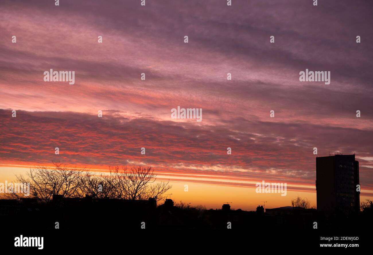 London, UK. 2 December 2020. Horizontal cloud layer is illuminated by the rising sun below the horizon creating a colourful pre-dawn sky over rooftops in south west London. Credit: Malcolm Park/Alamy Live News. Stock Photo