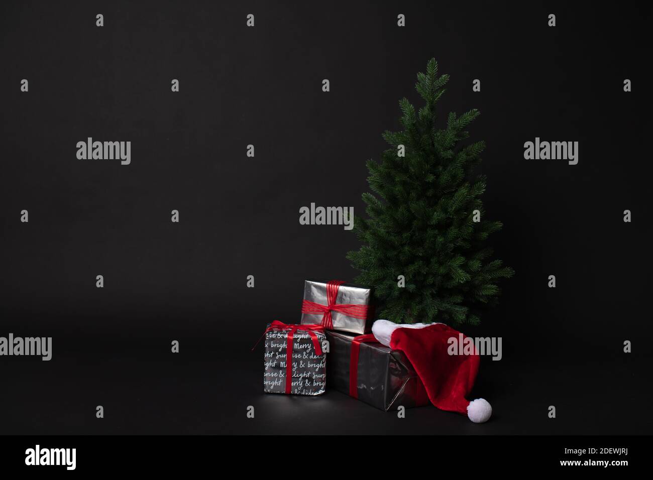Christmas tree gift boxes and Santa hat on black background Stock Photo
