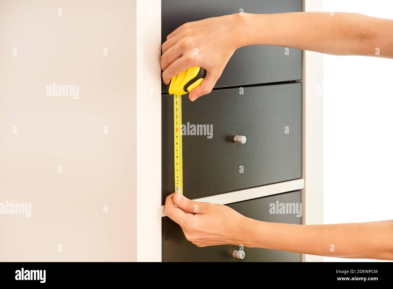 Female Hands Measuring The Height Of Drawers With An Automatic Tape Measure Stock Photo