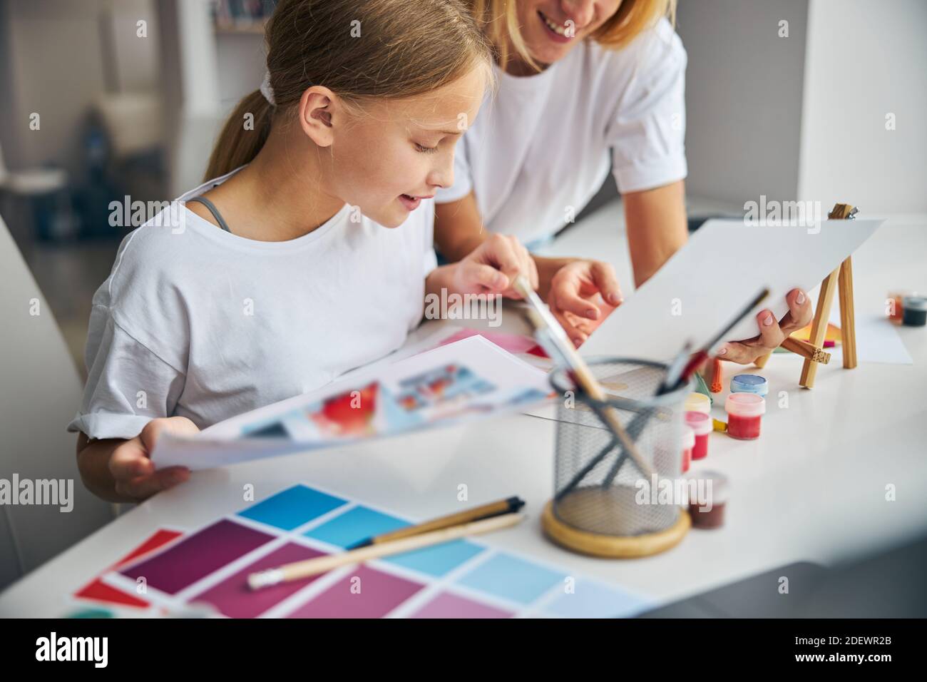 Daughter and her mother scrutinizing fashion sketches Stock Photo