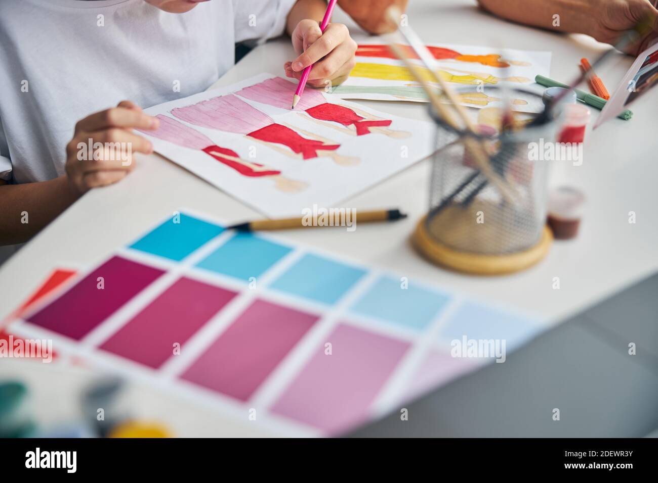 Girl drawing dress sketches with a pencil on the paper Stock Photo - Alamy