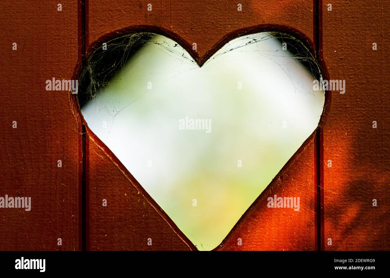 Heart shape cut out of a red wooden plank door on an outhouse toilet. close up. . High quality photo Stock Photo