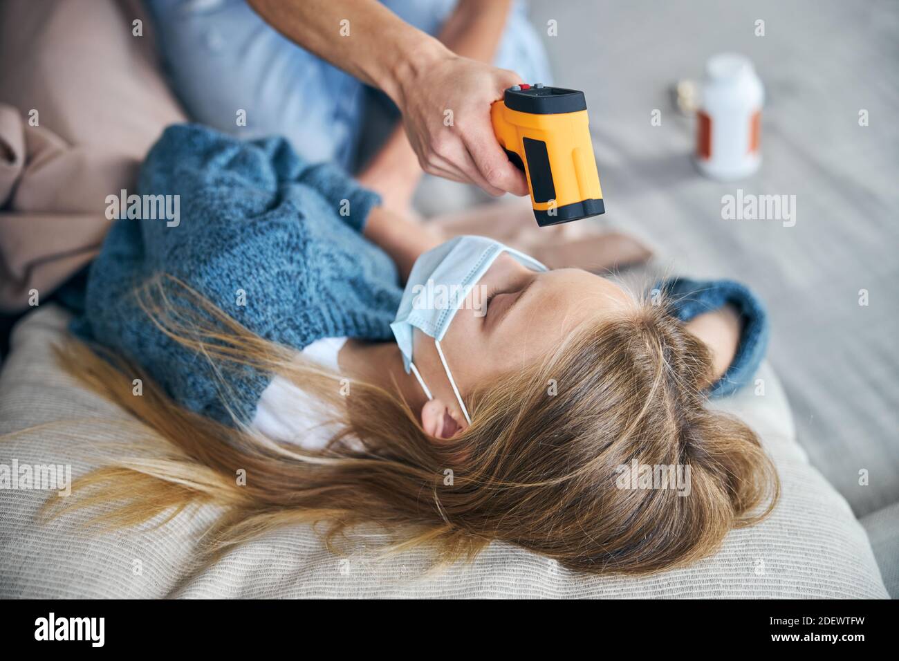 Female parent taking her child temperature with an infrared thermometer