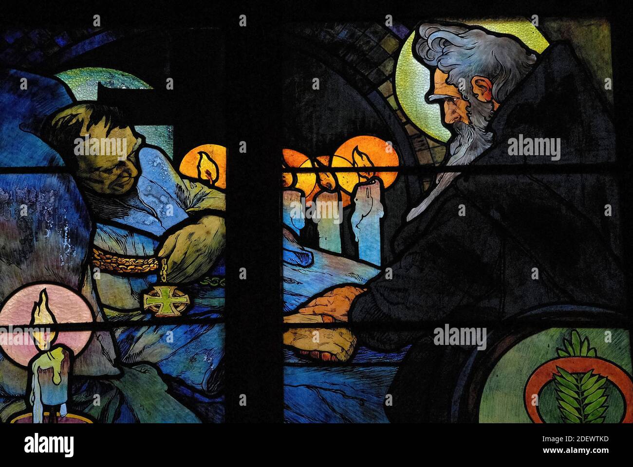 Candlelit vigil by deathbed of Byzantine theologian and missionary Saint Cyril, as depicted by influential Art Nouveau artist Alphonse Mucha in his vivid 1930 stained glass for the New Archbishop’s Chapel in the Cathedral of St Vitus in Prague, capital of the Czech Republic / Czechia. The artwork, an allegory of Christ blessing the Slavic nations, features scenes from the lives of ‘Apostles to the Slavs’ Cyril and his brother Methodius, as well as Czech patron saint Wenceslas, Duke of Bohemia, and his grandmother, St Ludmila. Stock Photo