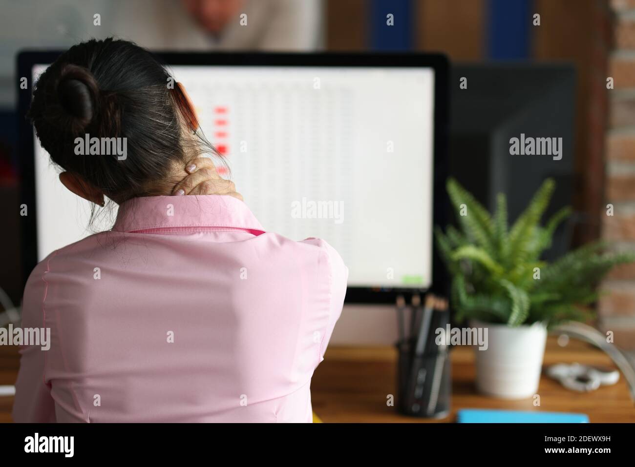 Tired woman sits at computer and massages pain in her neck Stock Photo ...