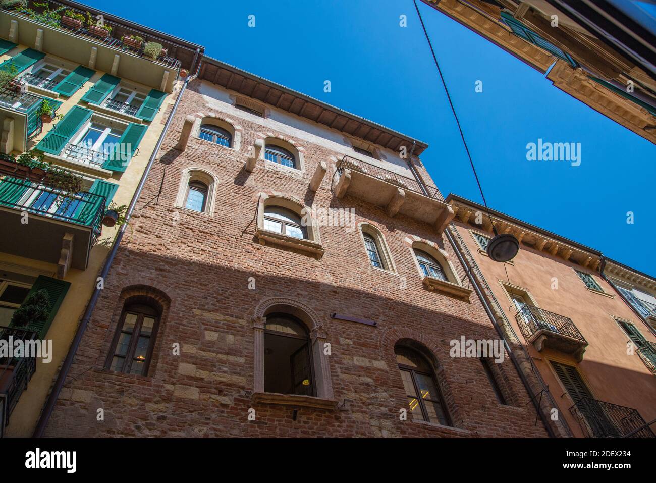 VERONA, ITALY - Aug 18, 2020: View from a narrow alley of a historic house front up to the sky with antique restored houses made of brick, metal and w Stock Photo