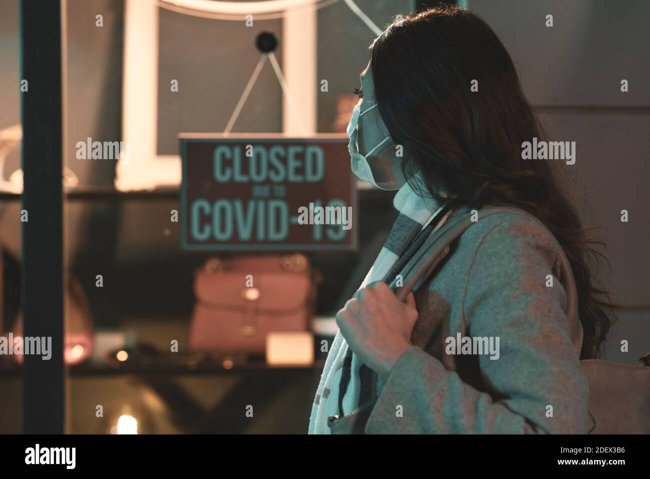 Store closed due to coronavirus covid-19 outbreak, a woman with surgical mask is reading the sign Stock Photo