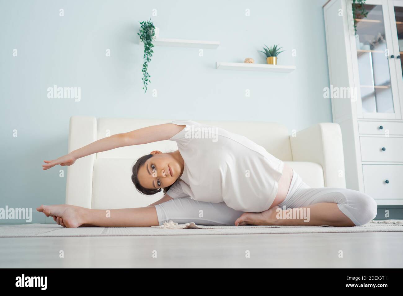 Beautiful pregnant woman exercising while sitting in lotus position. Pre-natal exercises. Stock Photo