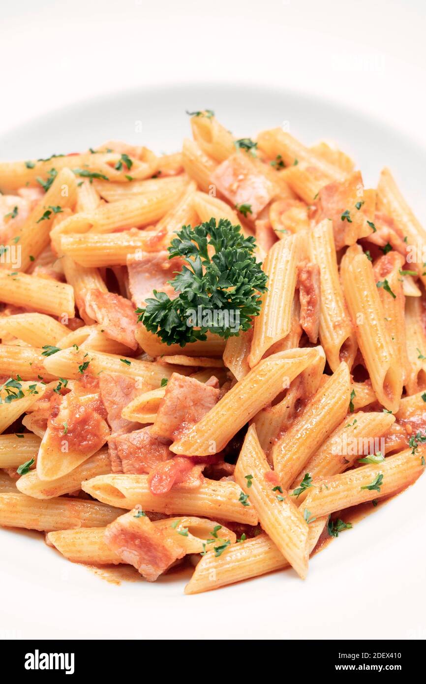 penne amatriciana organic tomato and ham sauce pasta dish on white table Stock Photo