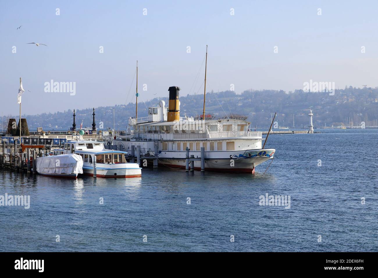 GENEVA, SWITZERLAND - Feb 20, 2018: City trip in Geneva during winter. Picture shows boats on the Lake of Geneva in Switzerland, with mountains in the Stock Photo