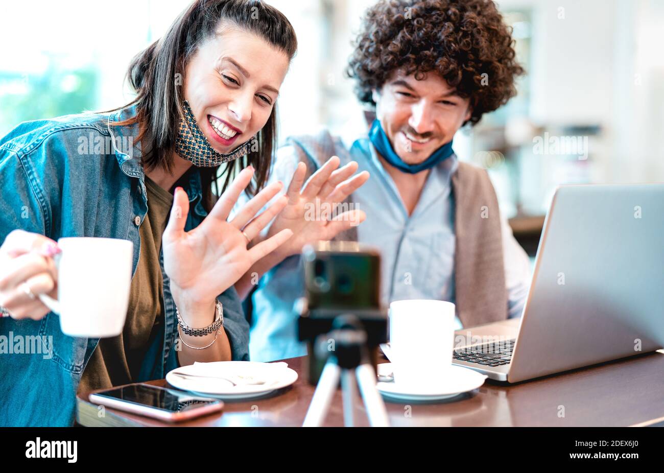 Young millenial couple sharing creative content with facemask - Digital marketing concept with next generation influencer having fun on video stream Stock Photo