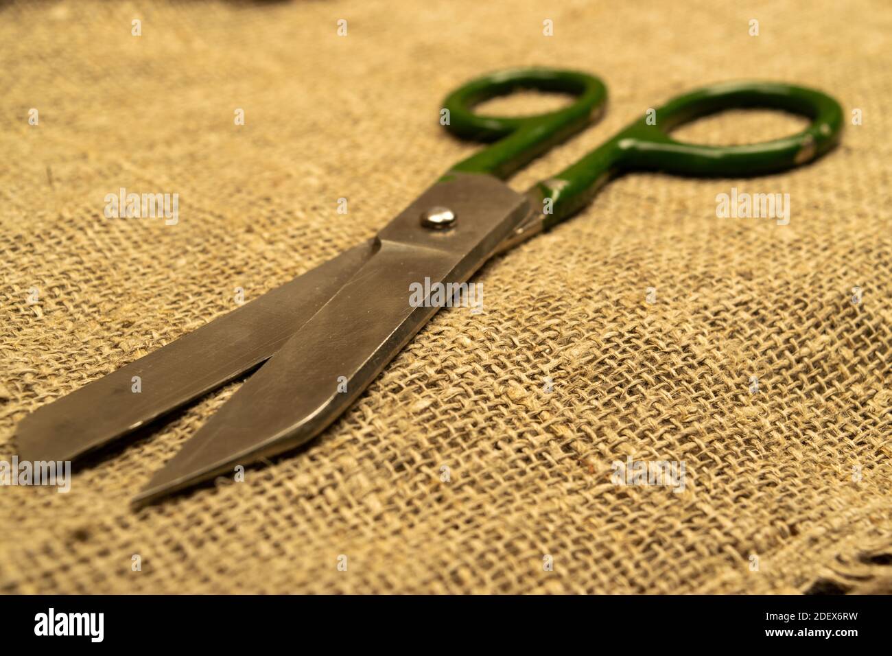 Large vintage scissors lie on rough homespun fabric. Close up Stock