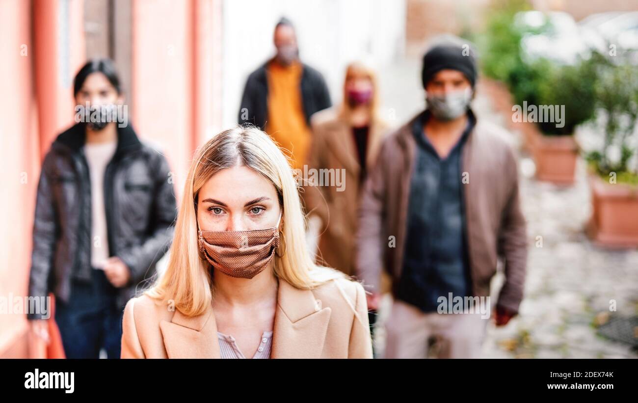 Urban crowd of young people walking on city street covered by face mask - New normal social life concept with citizens on worried anxiety mood Stock Photo