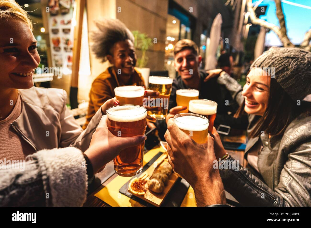 Happy friends drinking beer at brewery bar out doors on night mood - Friendship lifestyle concept with young people enjoying time together Stock Photo