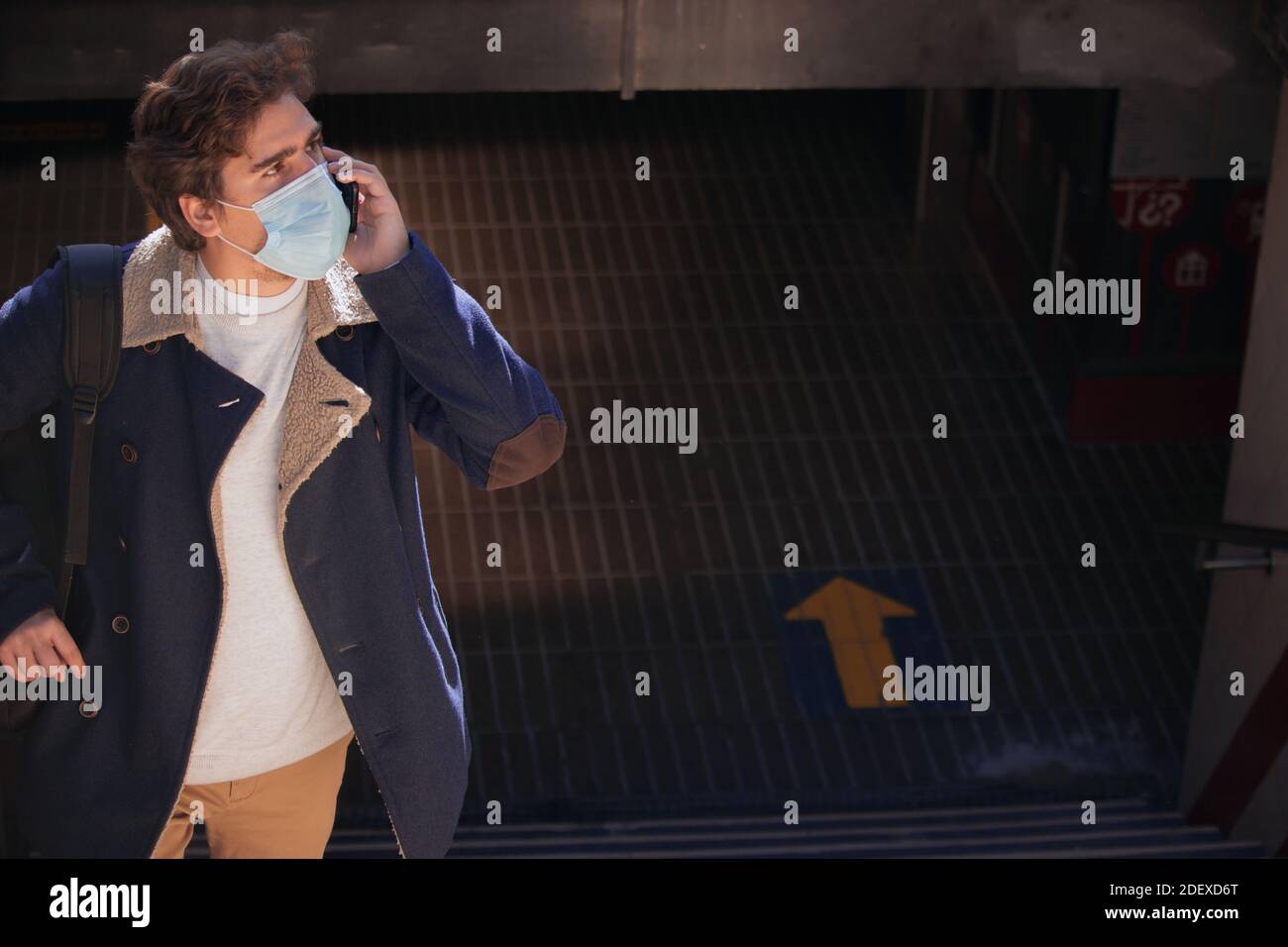 Recognizable young busy man with a mask talking on the phone outside the underground in the city center. Working and business day 2021. Stock Photo