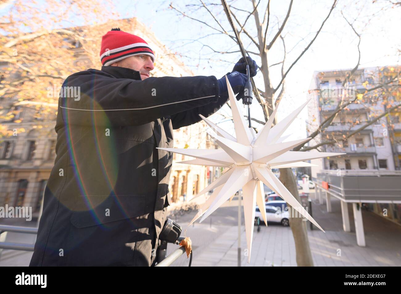 Dresden, Germany. 02nd Dec, 2020. Jens Kruste, a decorator, hangs a Herrnhut star from a lifting platform on the main street on a span. The Christmas illumination is part of the Christmas market 'Augustusmarkt', which cannot take place as planned this year due to the partial lockdown. Credit: Sebastian Kahnert/dpa-Zentralbild/dpa/Alamy Live News Stock Photo