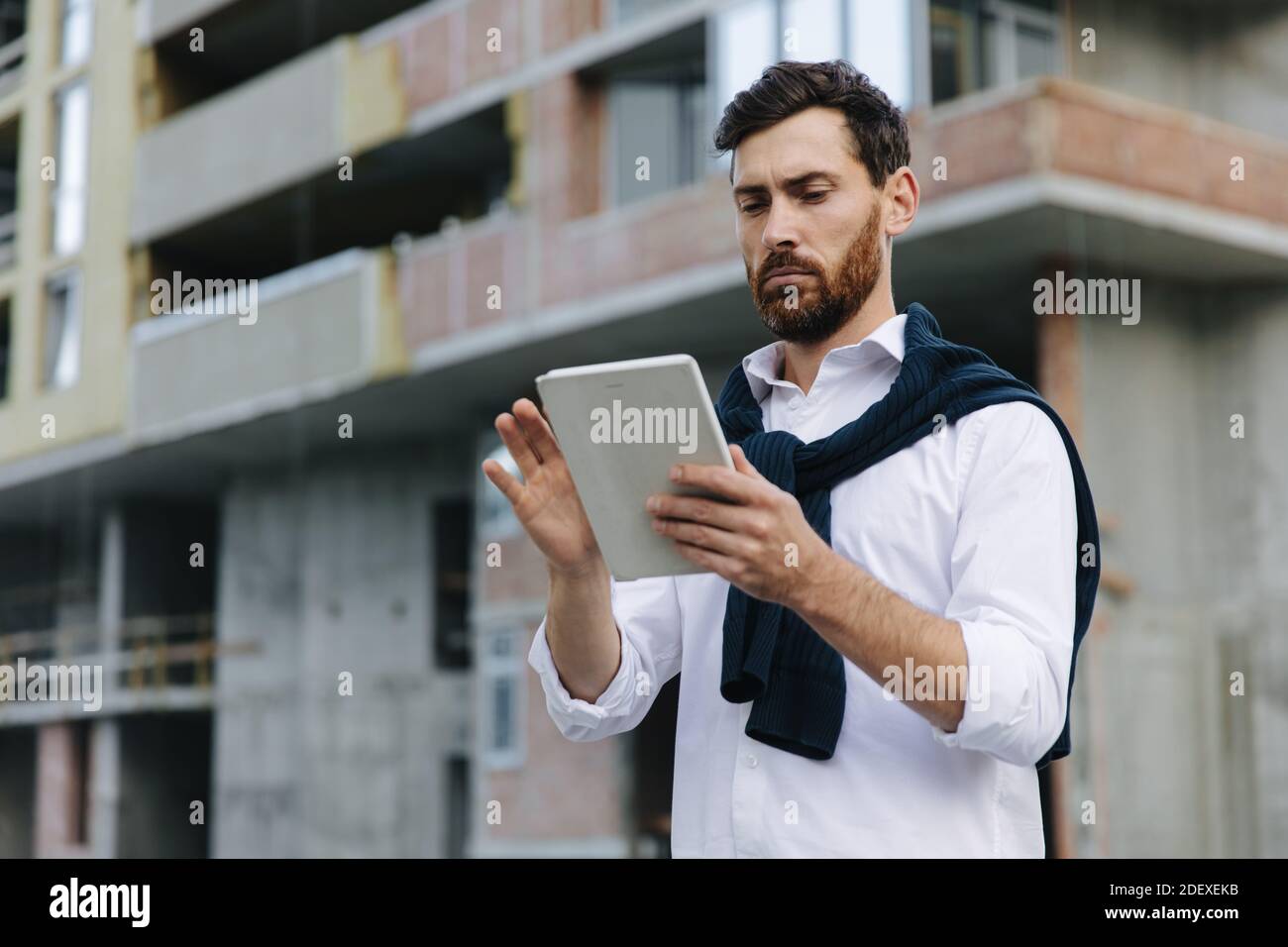 Competent engineer looking at tablet while working outdoors Stock Photo