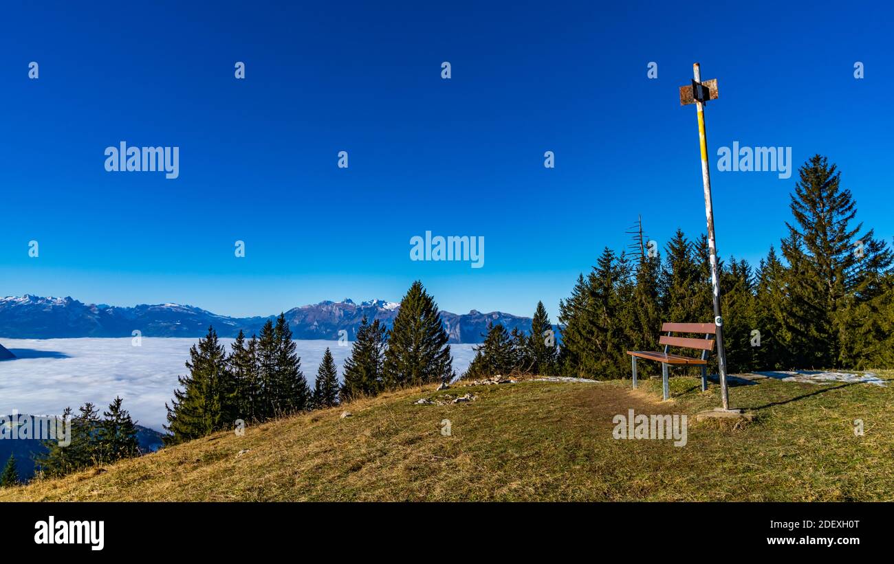 Bank auf dem Alpkopf, mit Aussicht auf die Schweizer Berge, über das vernebelte Rheintal. park bench on the top of the mountain, over sea of mist Stock Photo