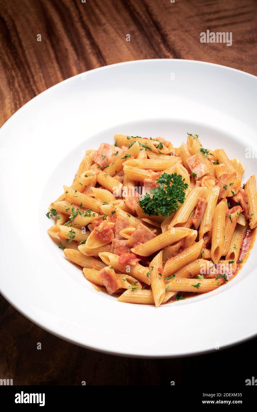 penne amatriciana tomato and ham sauce pasta on wood table background Stock Photo