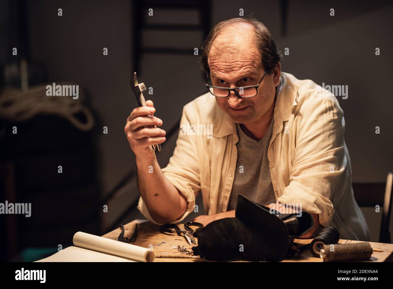 an experienced manual Shoe maker shows his students how to work with tools in the Studio at a table Stock Photo