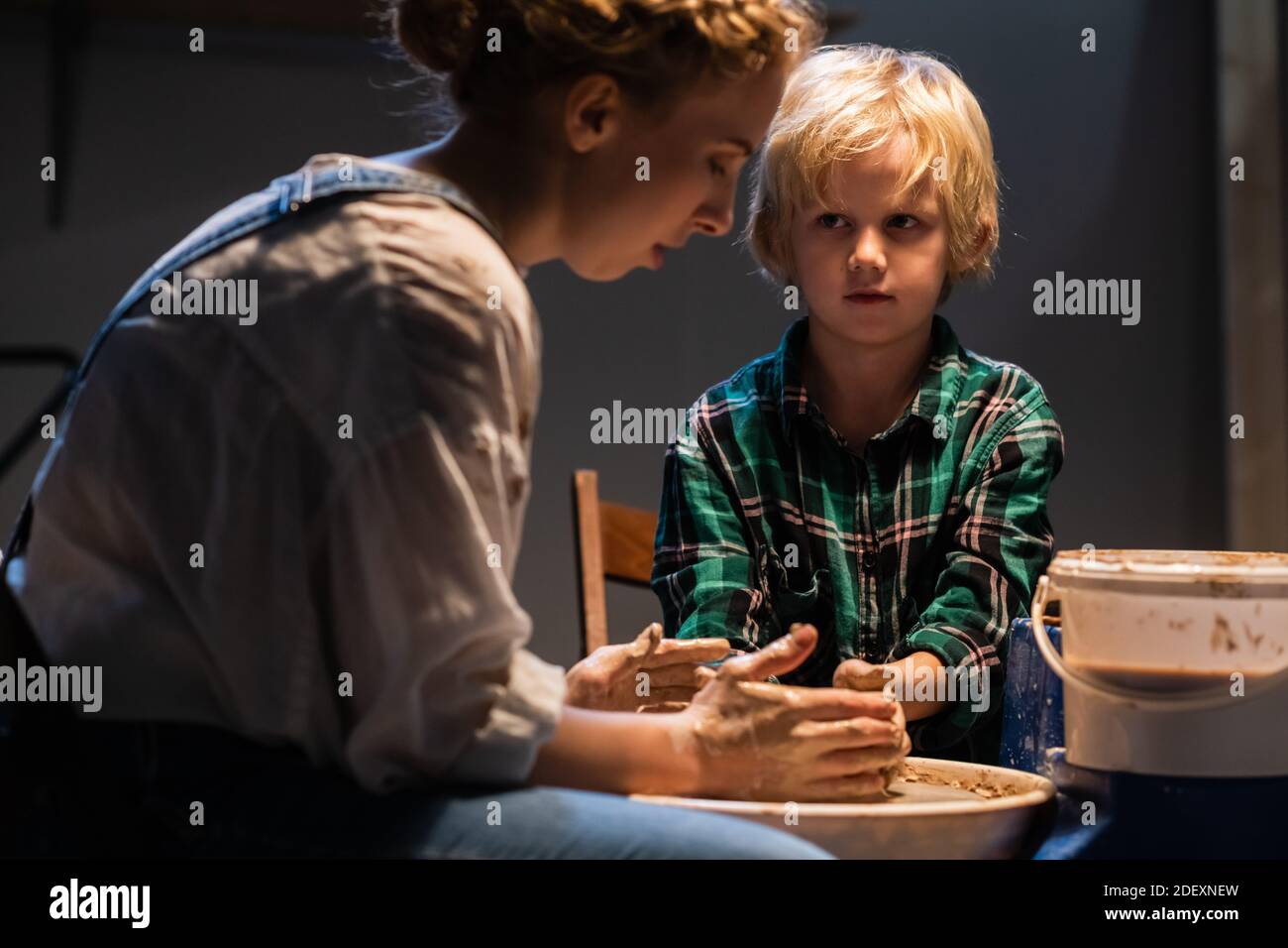 a young woman potter helps a cute boy to make a gift for his mother out of clay Stock Photo