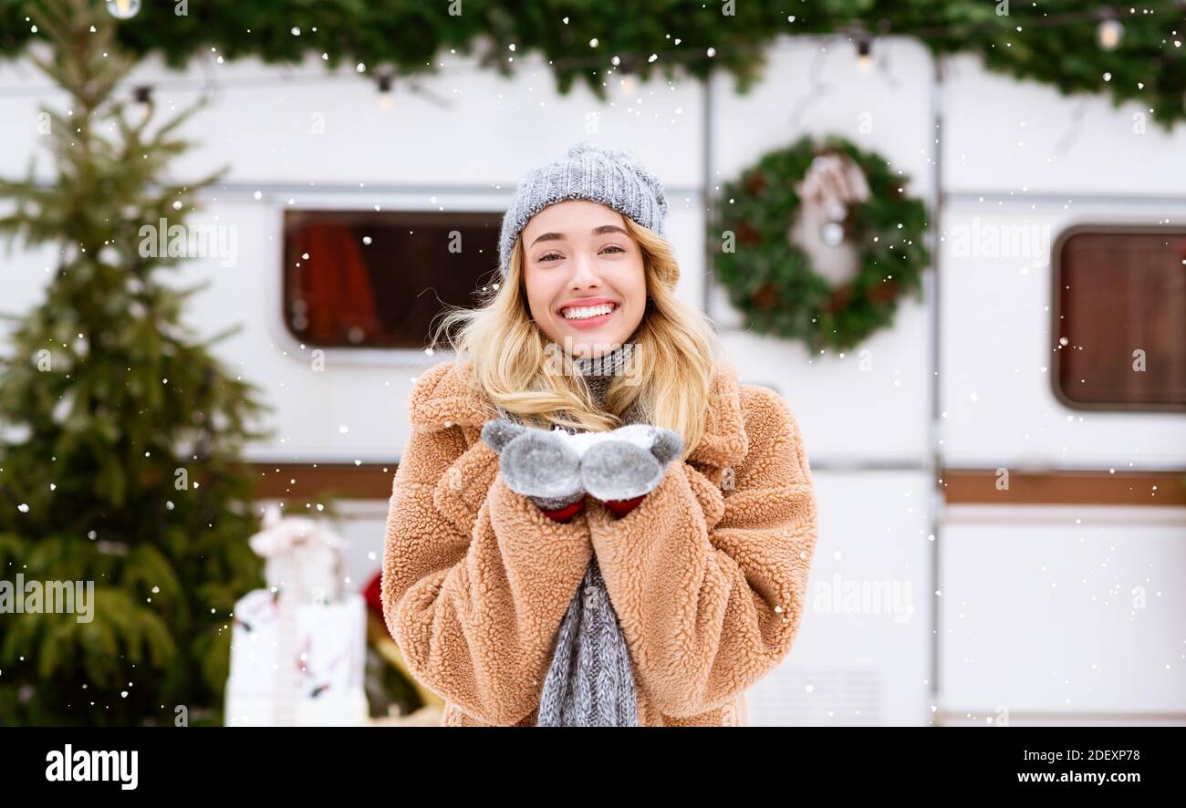 First Snow. Happy young blonde woman enjoying snowfall at winter campsite Stock Photo