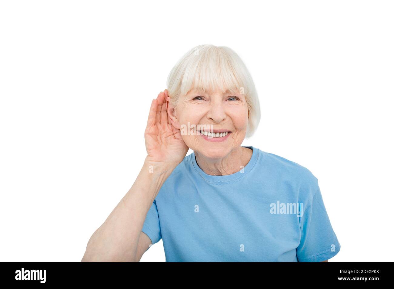 Deafness concept. Smiling elderly woman with a hand over ear listening sounds and voices, isolated on white Stock Photo