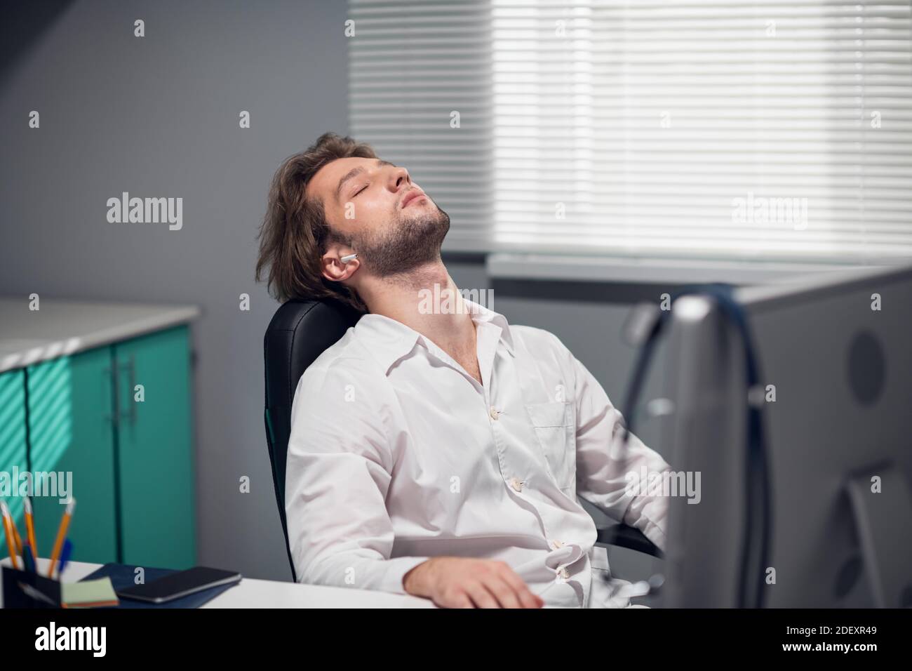 Male doctor sitting at his desk in a medical clinic, leaning his head