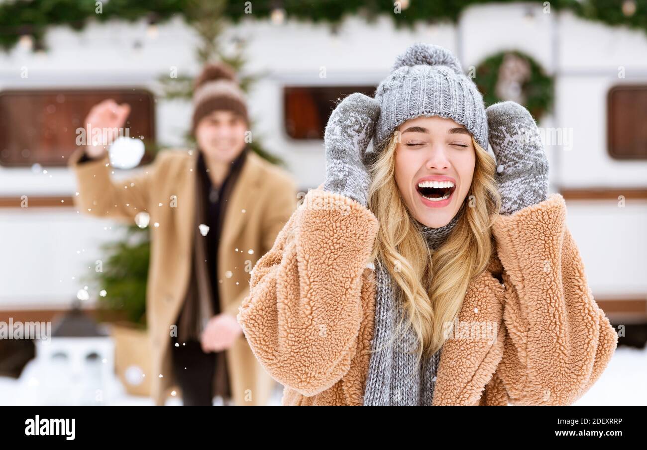 Outdoor Fun. Happy Cheerful Young Couple Throwing Snowballs At Each Other Stock Photo
