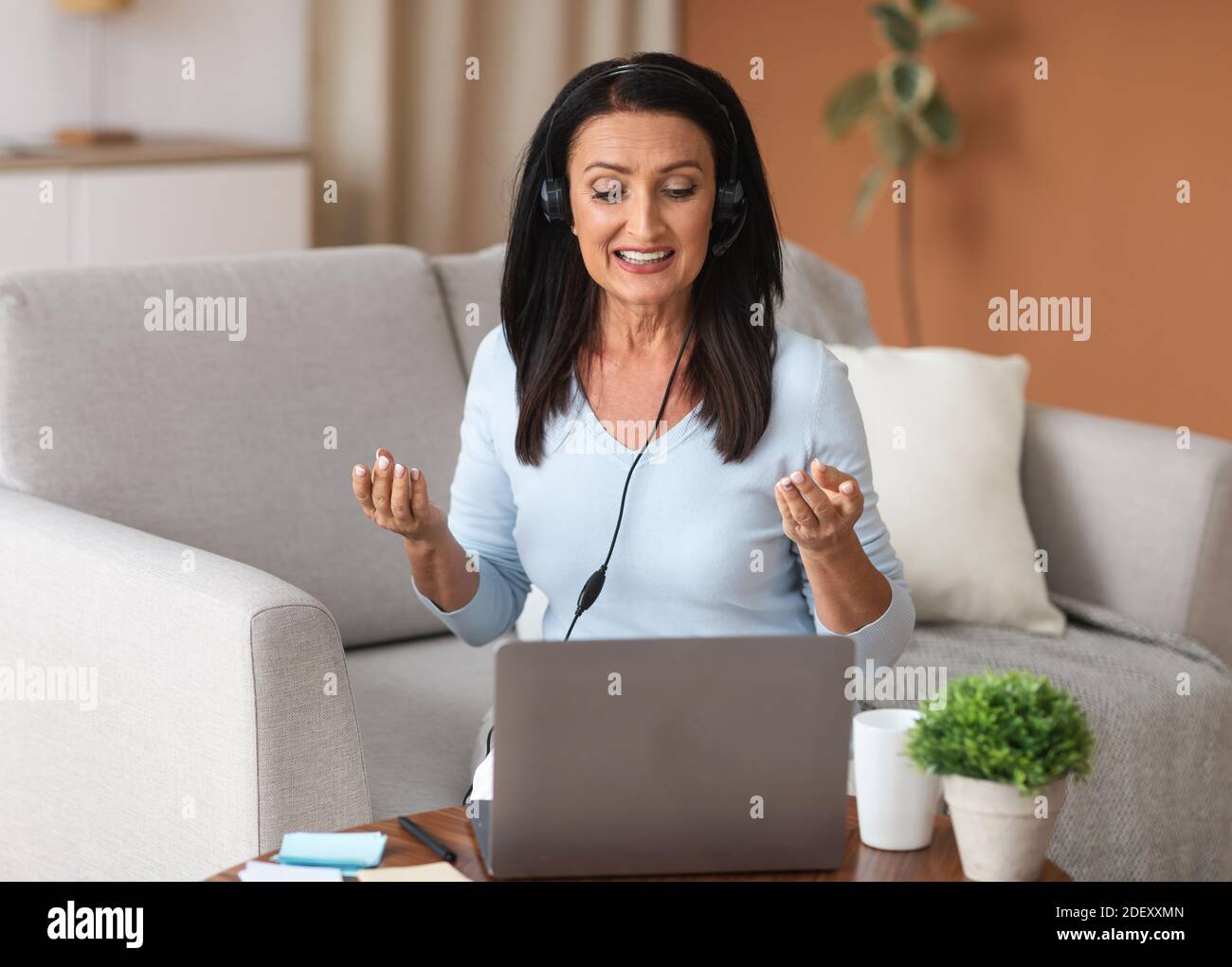 Woman in headset having video call on computer Stock Photo