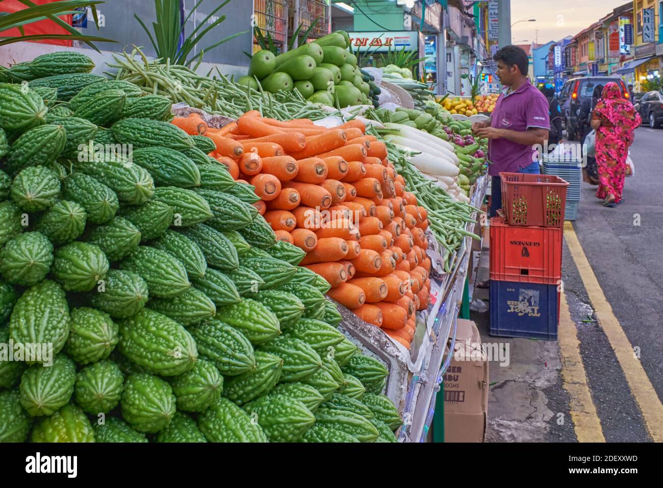 An Indian man buying vegetables at an Indian-run vegetable stall; left: karela or bitter gourd; Dunlop Street, Little India, Singapore Stock Photo