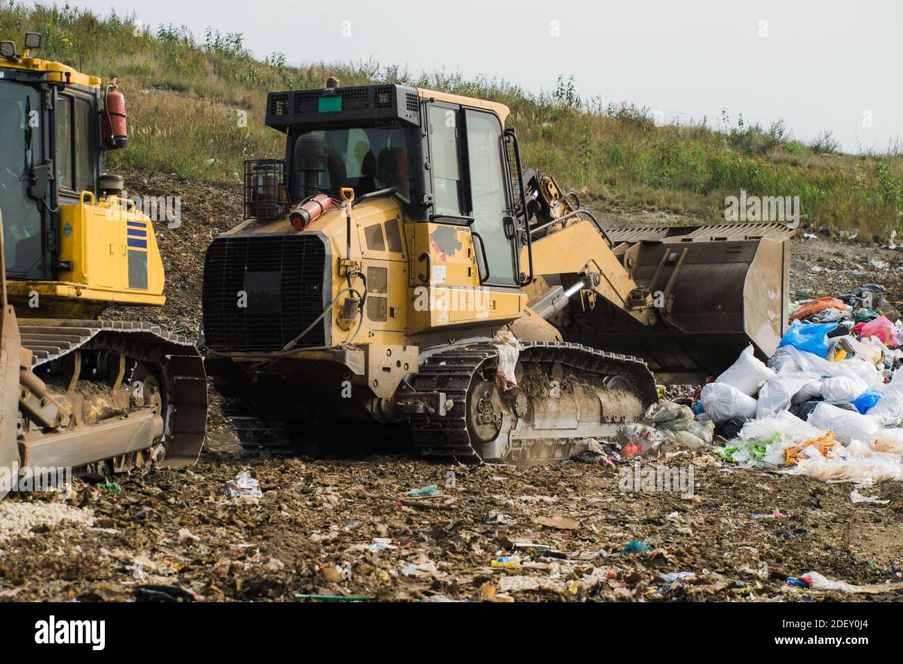 Yellow tractors work on dump. Household garbage. Waste sorting on