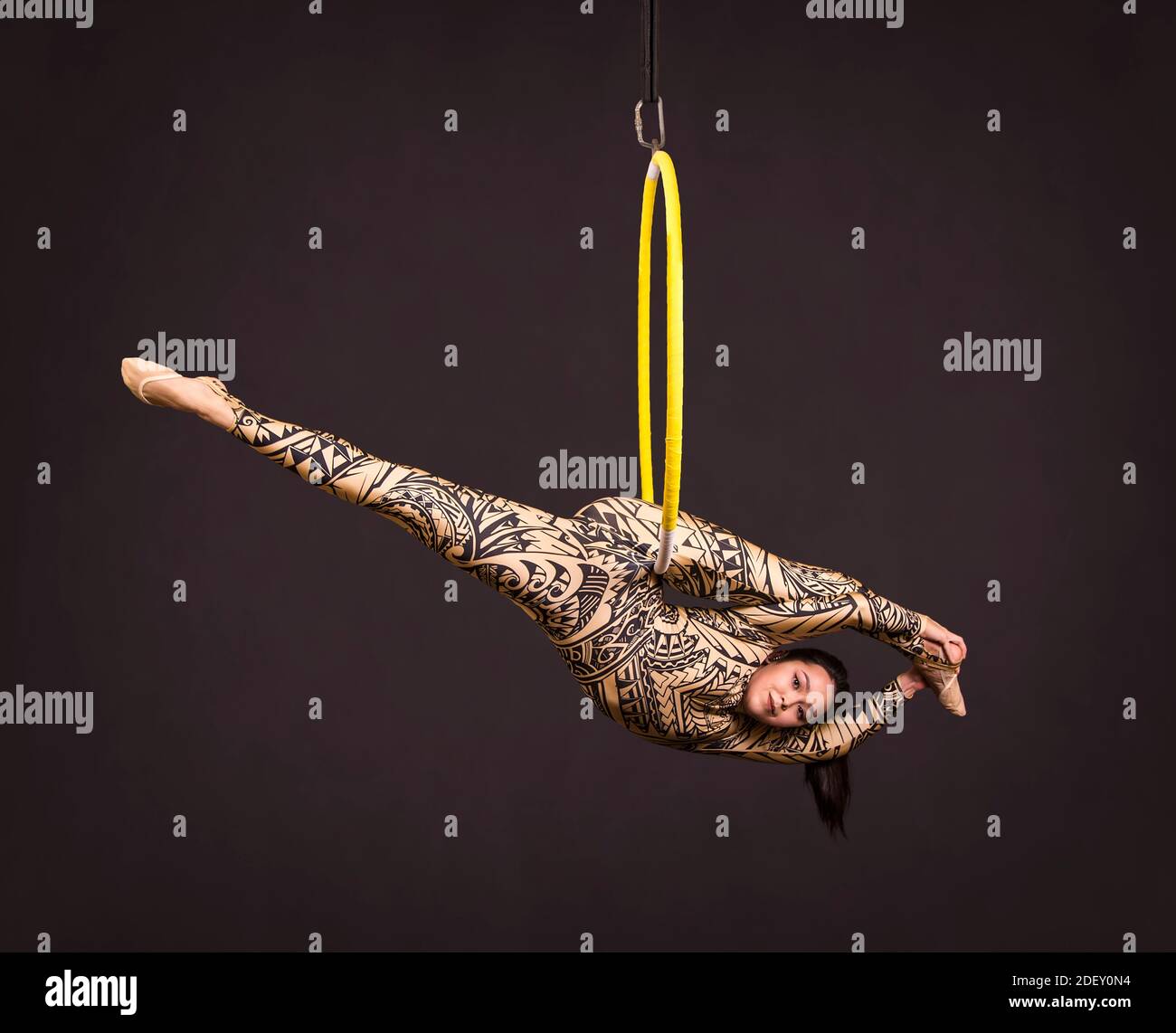 A young woman in a suit with a print performs acrobatic elements in the ...