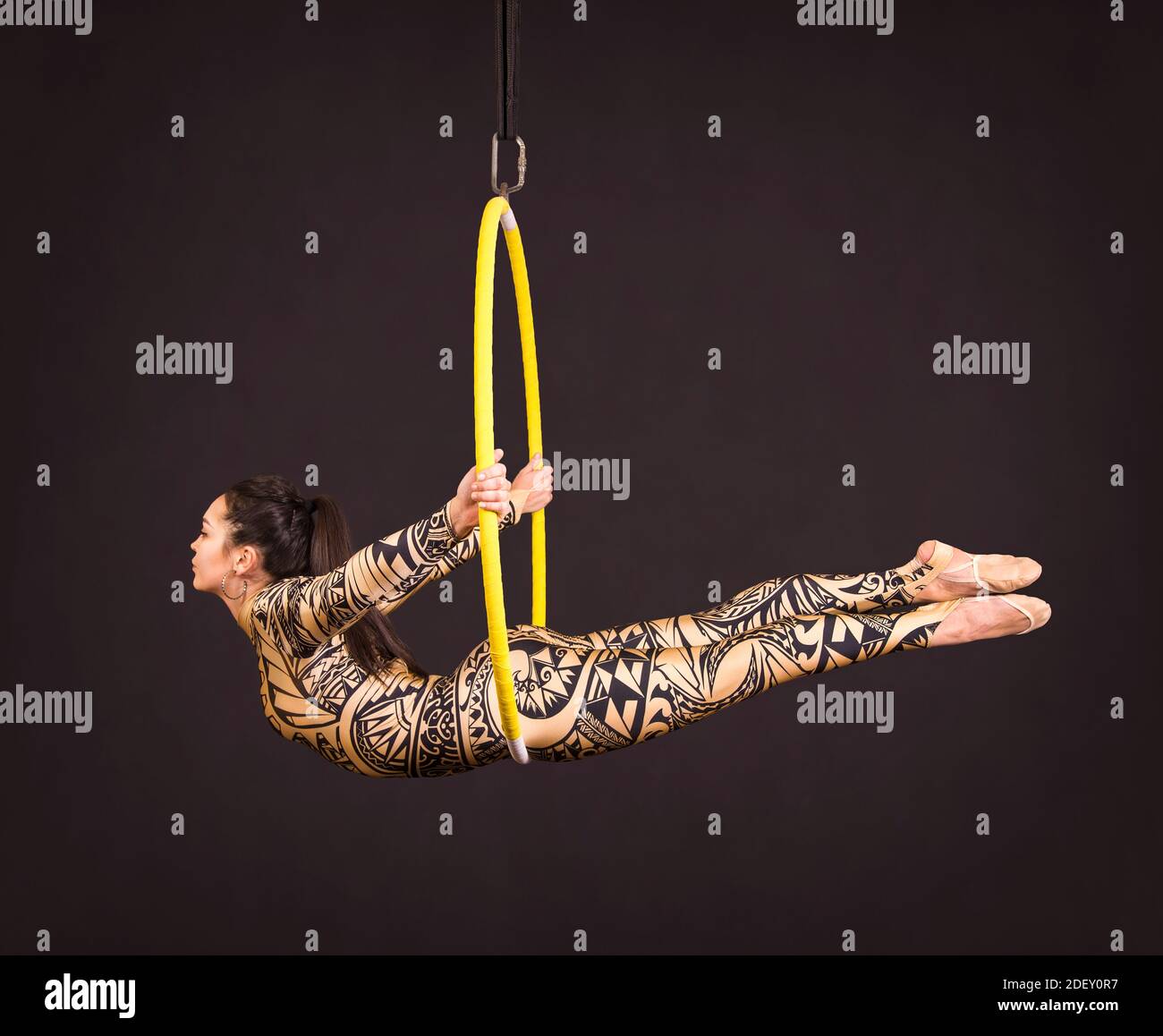 A young woman in a suit with a print performs acrobatic elements in the ...