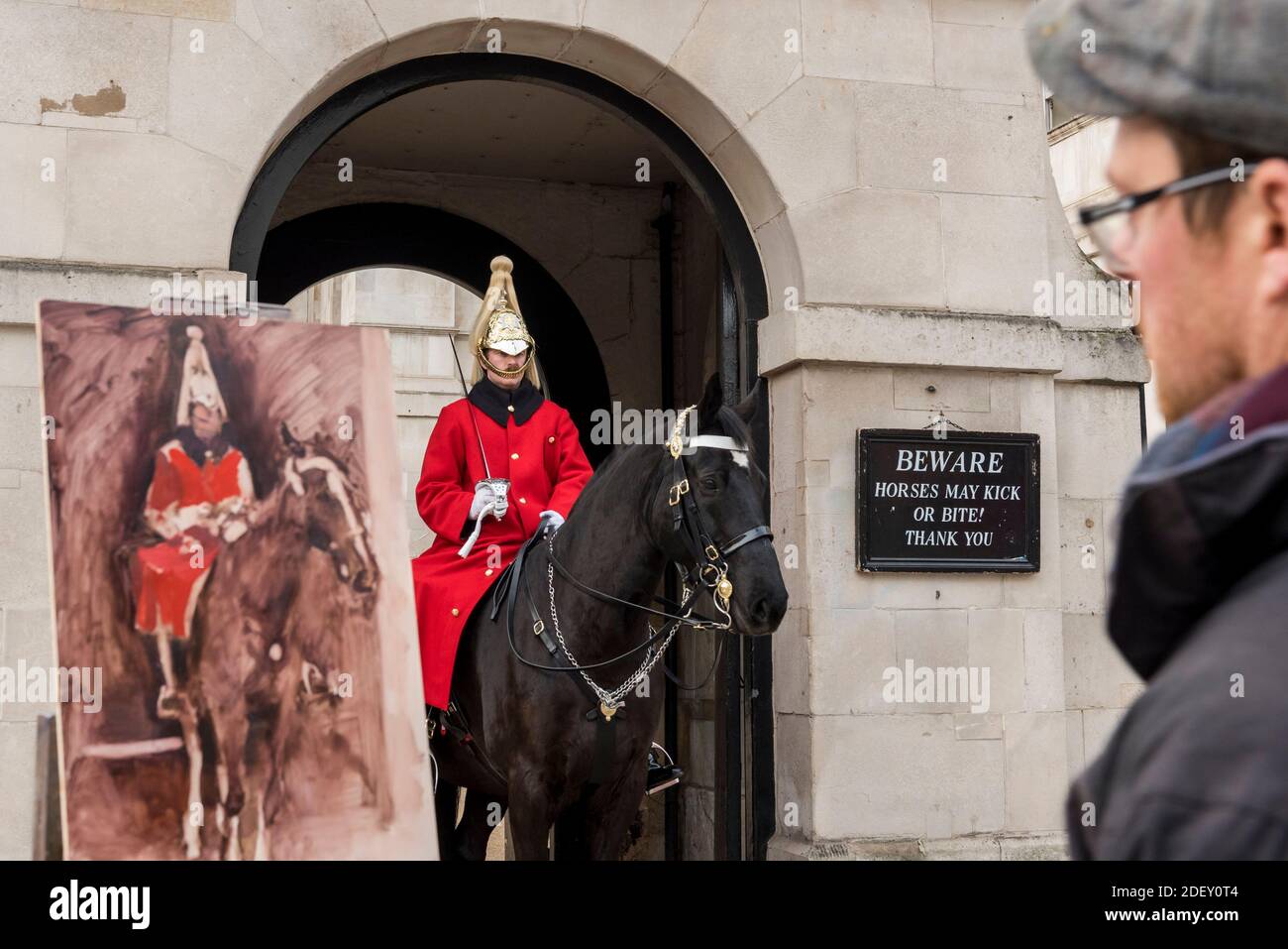 London, UK.  2 December 2020. Artist Rob Pointon creates a painting of a member of the Queen's Life Guard, part of the Household Cavalry, wearing their traditional red tunic, standing guard outside Horse Guards Parade. Credit: Stephen Chung / Alamy Live News Stock Photo