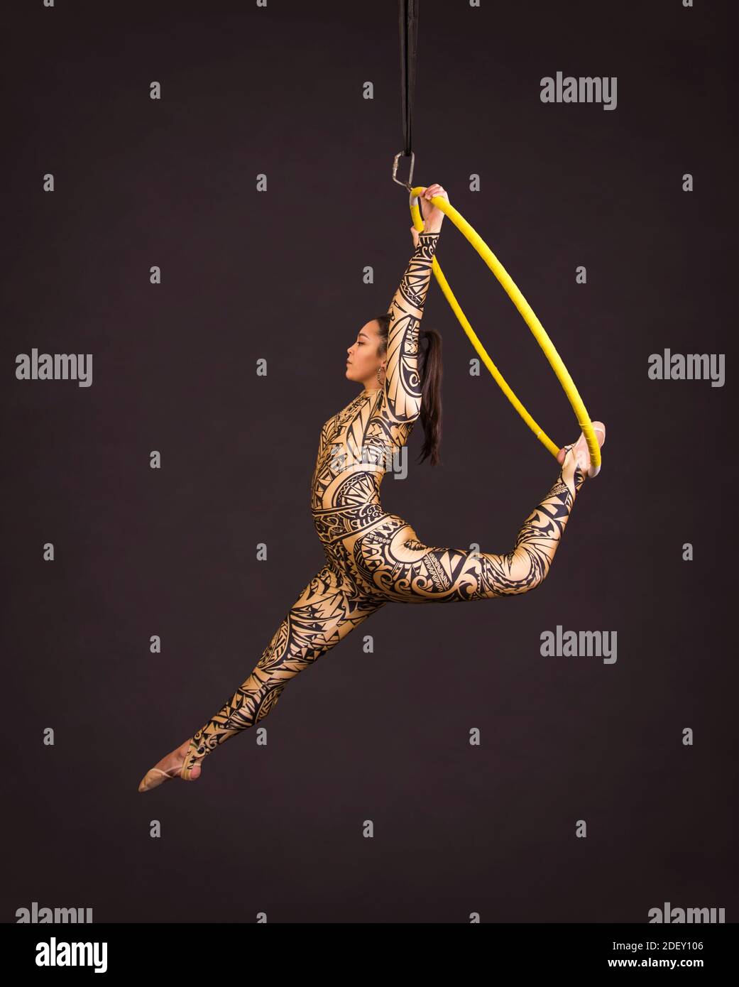 A young woman in a suit with a print performs acrobatic elements in the ...