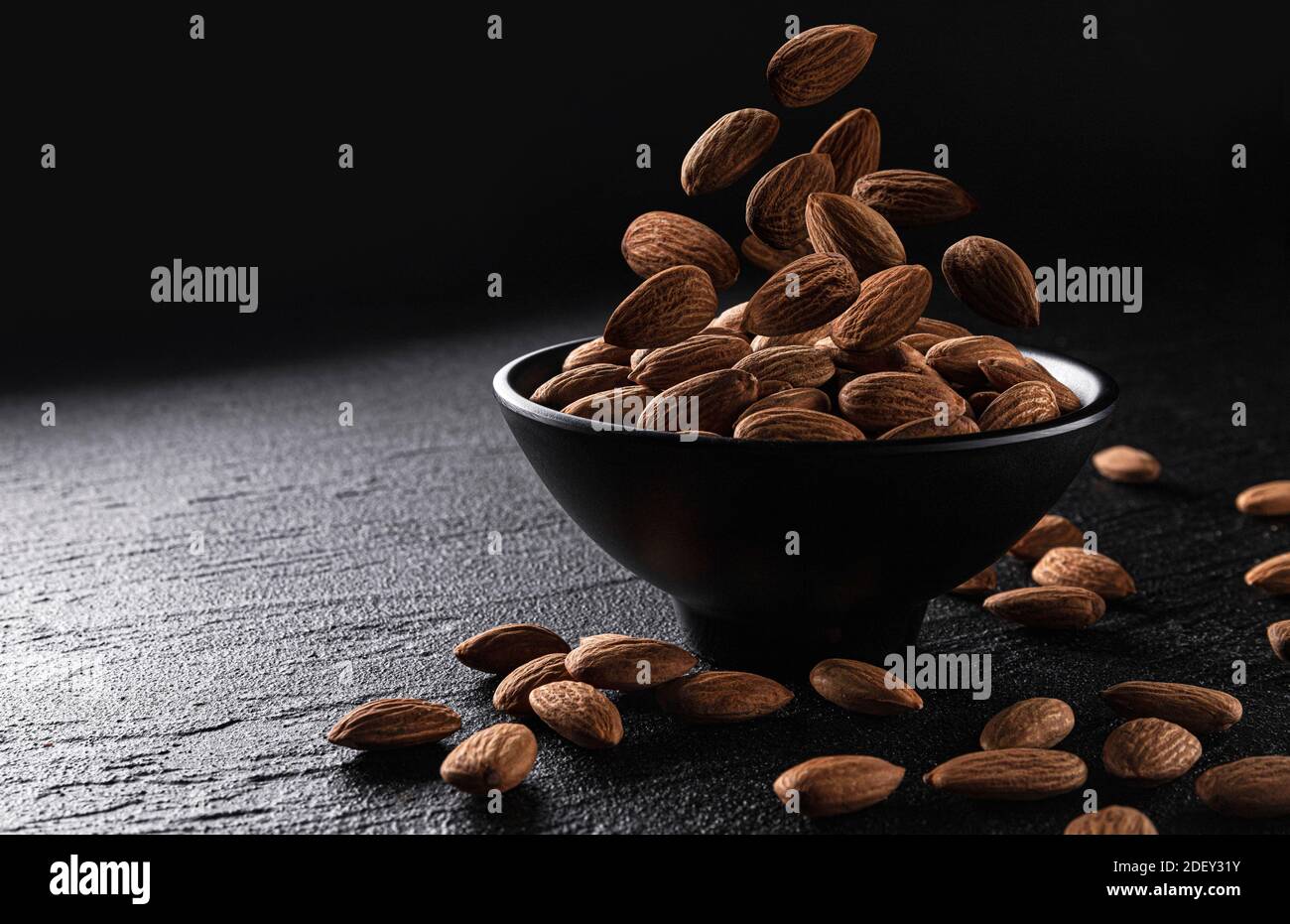 Falling almond nuts on black background with copy space Stock Photo