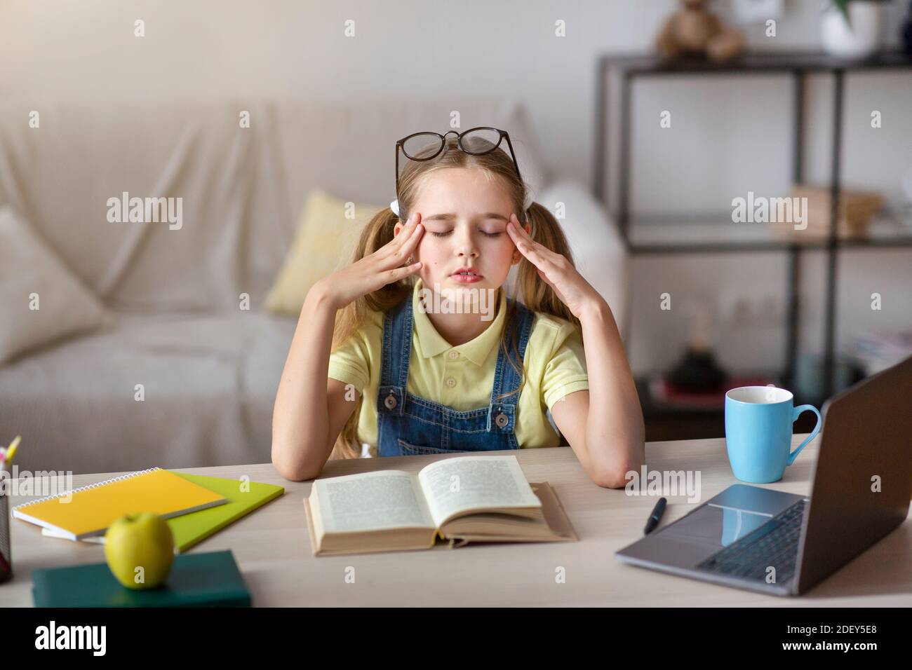 Tired girl massaging temples sitting at desk with laptop Stock Photo ...