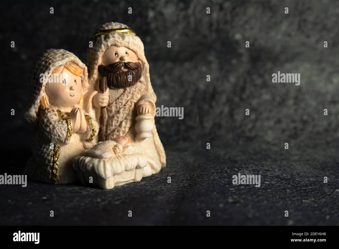 Representation of a Christmas nativity scene with the figures of baby Jesus, Mary and Joseph on a rock background. Phrase space on the right. Christma Stock Photo