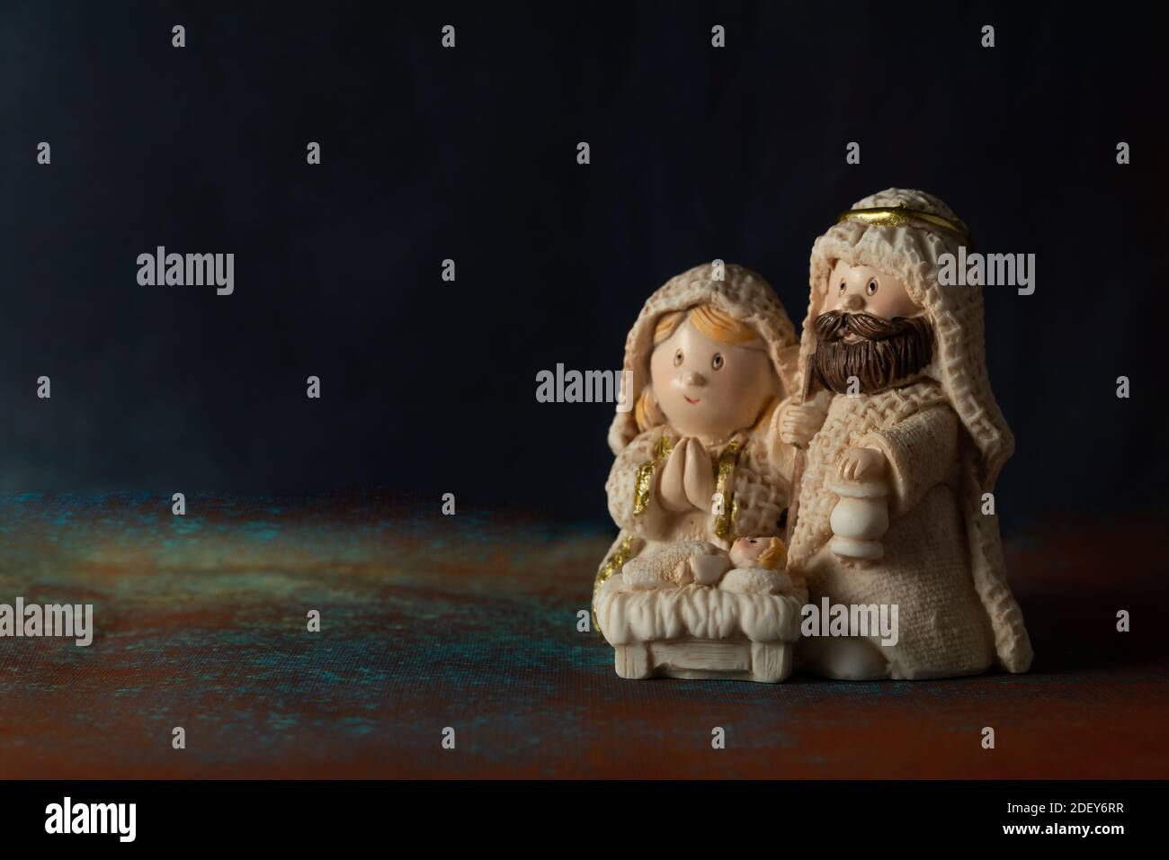 Representation of a Christmas nativity scene with the small figures of baby Jesus, Mary and Joseph on a rock background. Phrase space on the left. Chr Stock Photo