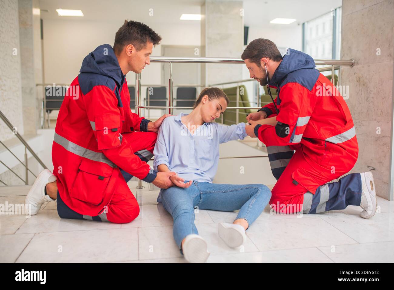 Ambulance crew in red uniform making an injection to a woman Stock ...