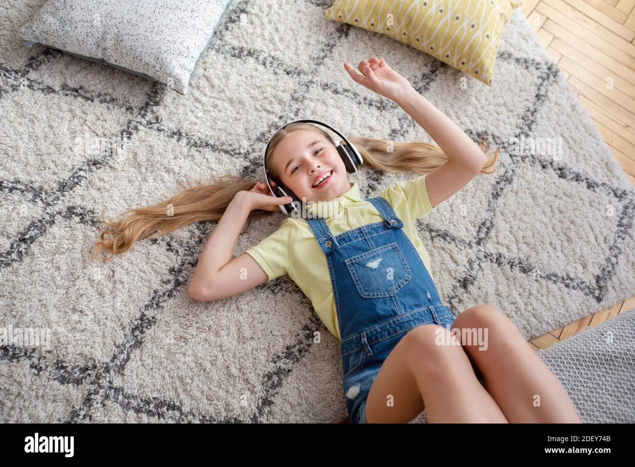 Teenage girl lying on floor carpet, listening to music Stock Photo - Alamy