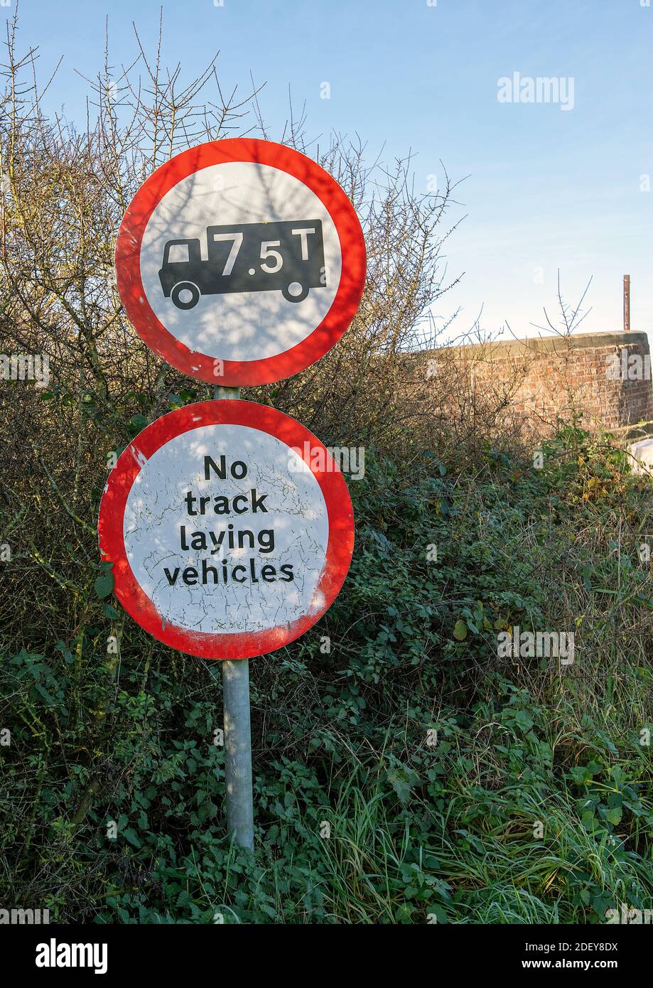 Warning signs for a 7.5 ton limit and no track laying vehicles on approce to a weak bridge Stock Photo