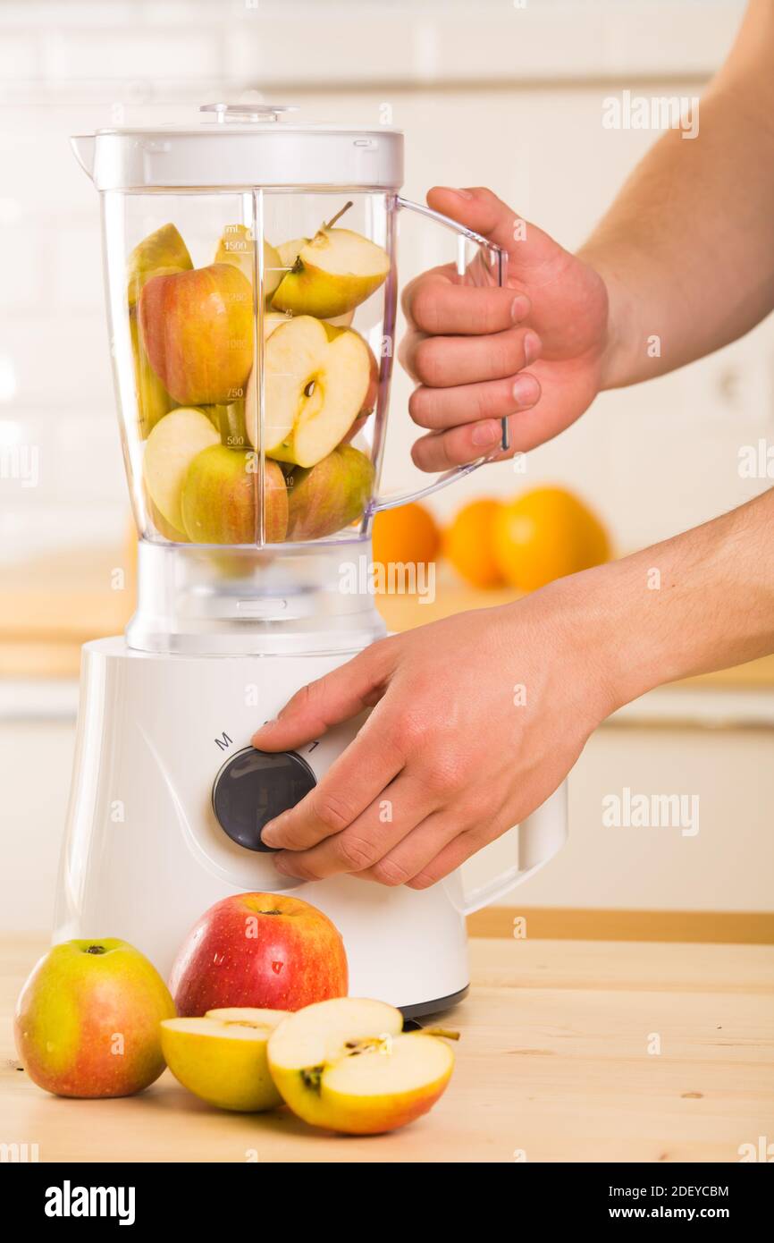 Young man cooking apple smoothie in blender Stock Photo - Alamy