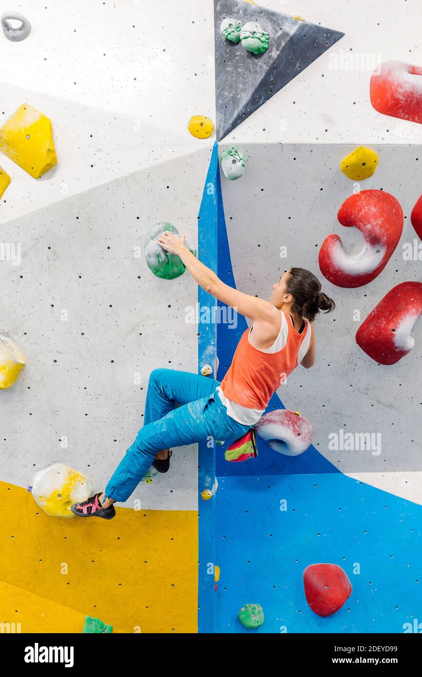 Stock photo of an adult woman rock climbing indoors. She is wearing a