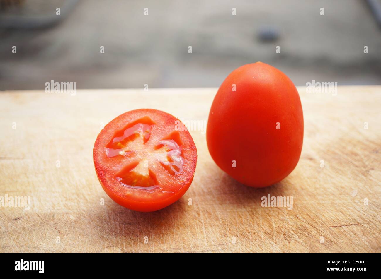 A top view closeup of a fresh cherry tomato on a wooden cutting board ...